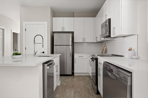 A modern kitchen with white cabinets and stainless steel appliances.