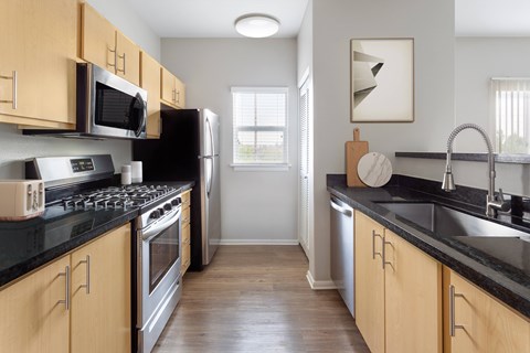 A kitchen with wooden cabinets and black countertops.