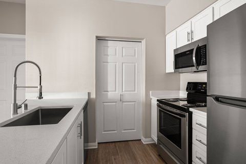 A kitchen with a sink, stove, and oven.