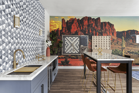 A kitchen with a table and chairs in front of a desert mural.