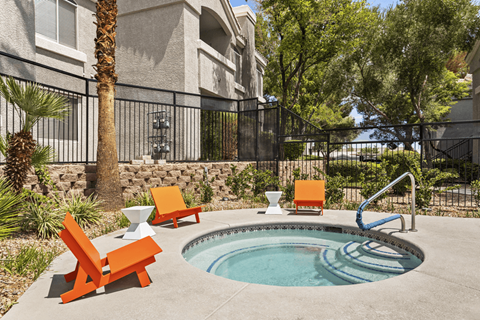 A pool with a slide and chairs in front of a building.