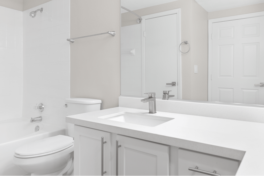 A white bathroom with a toilet, sink, and mirror.