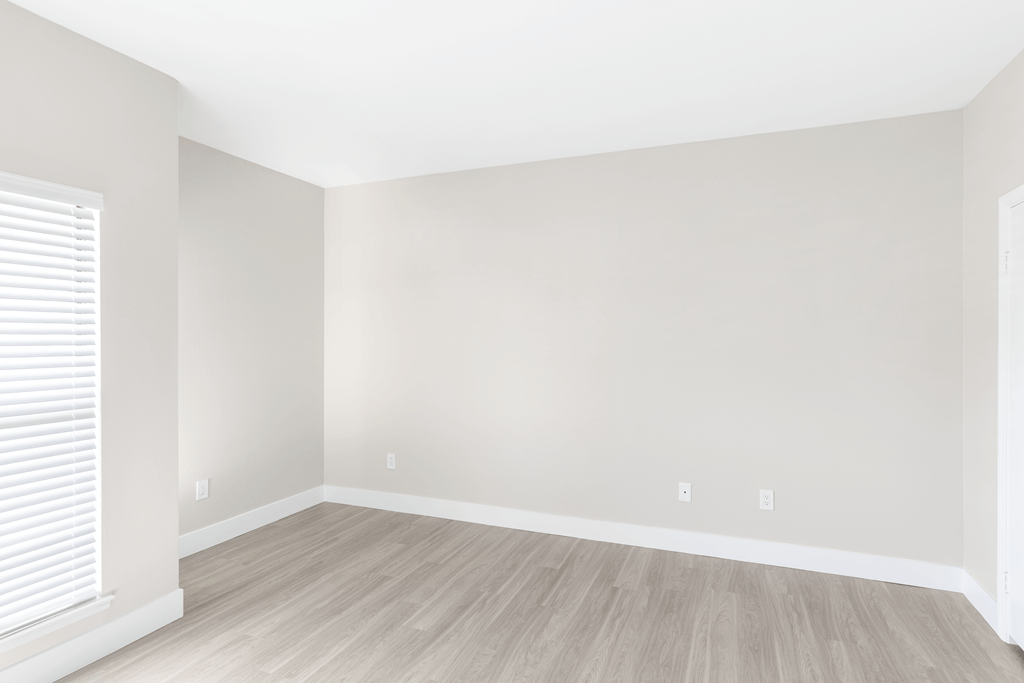 A room with a window and wooden flooring.