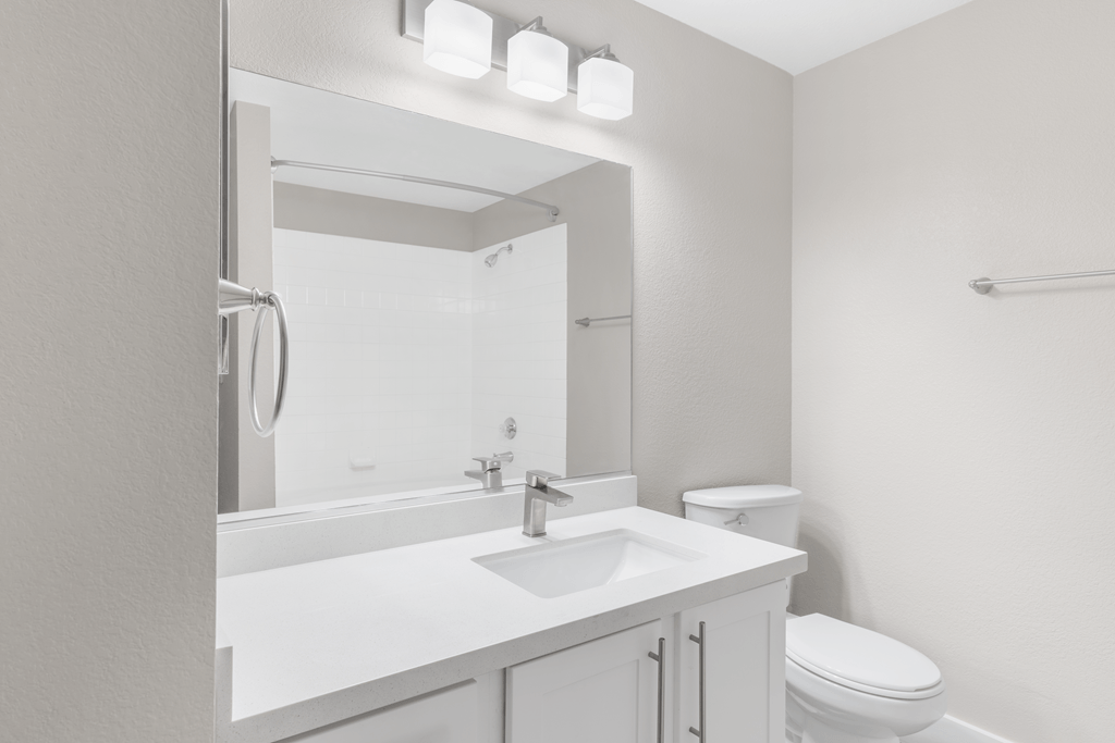 A white bathroom with a toilet, sink, and mirror.