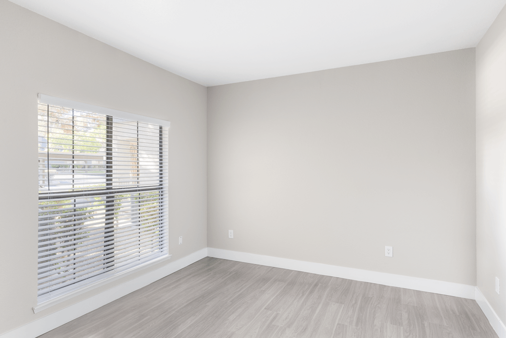 A room with a window and wooden flooring.