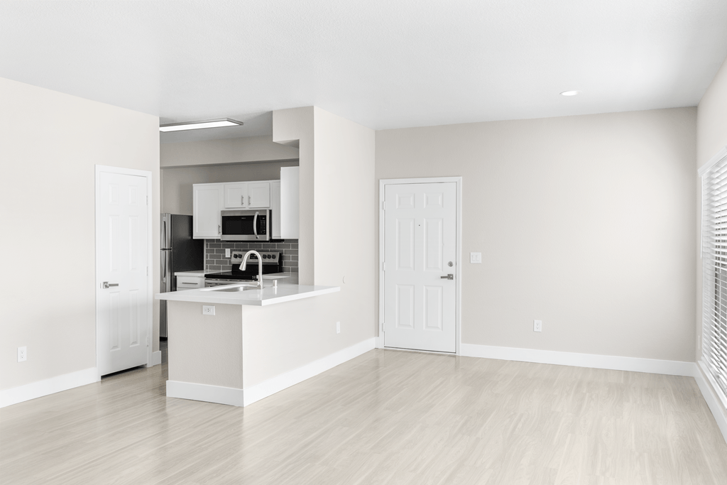 A kitchen with white cabinets and a white fridge is shown.