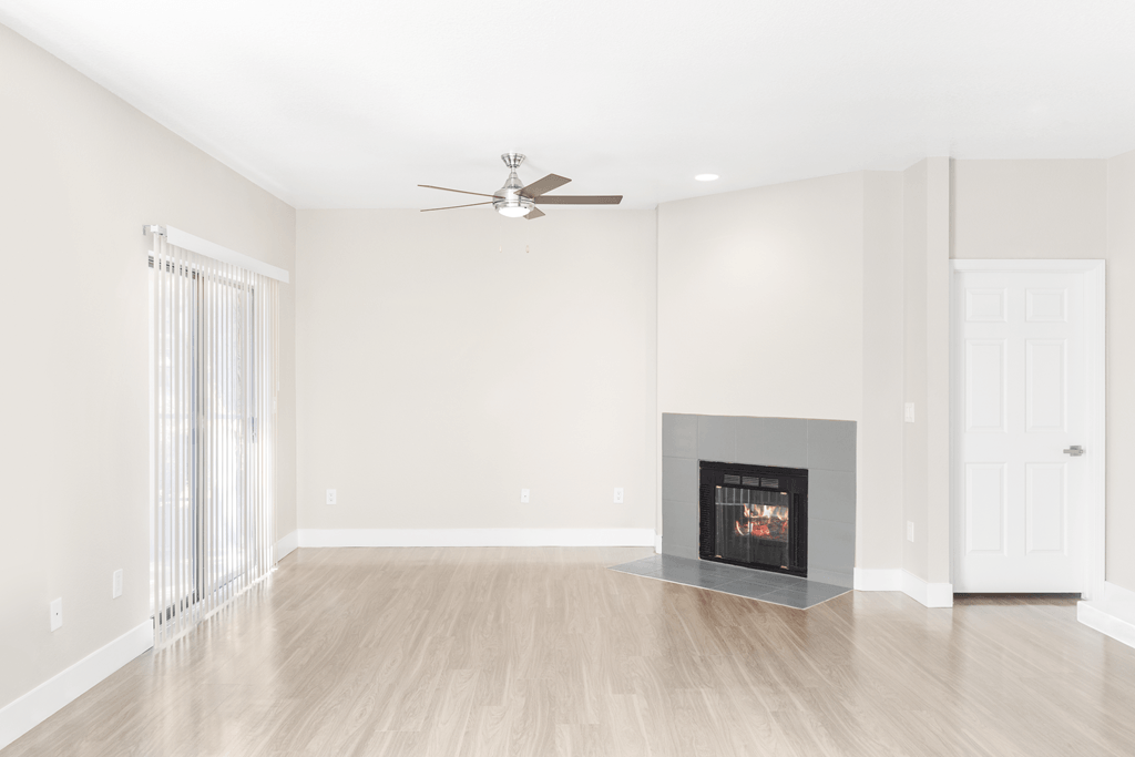 A living room with a fireplace and a ceiling fan.