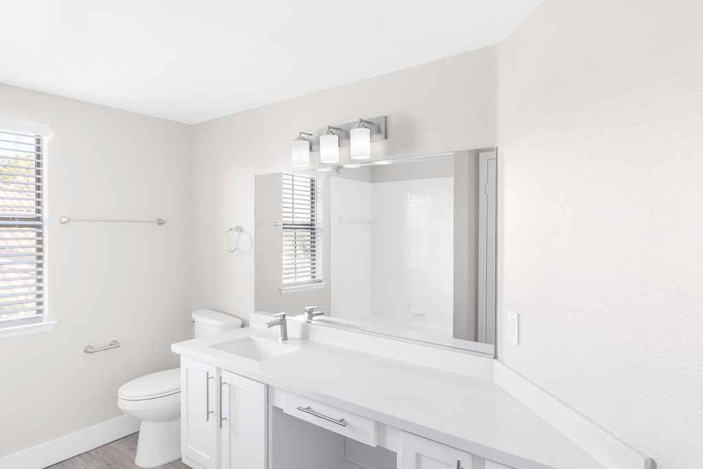 A white bathroom with a toilet, sink, and mirror.