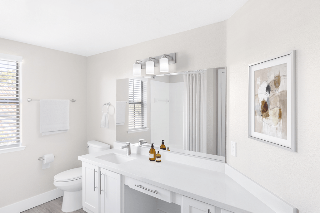 A white bathroom with a toilet, sink, and mirror.