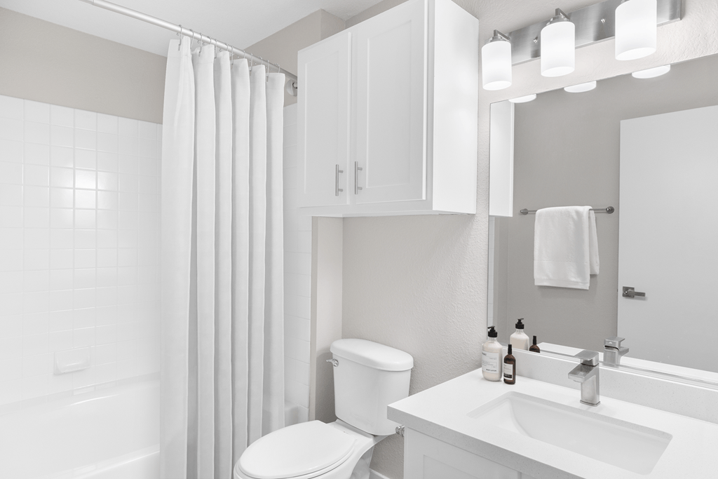 A white bathroom with a toilet, sink, and shower.