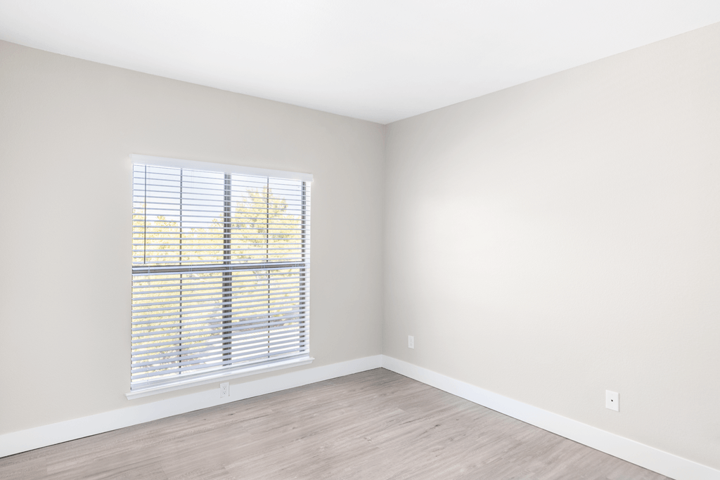 A room with a window and wooden flooring.