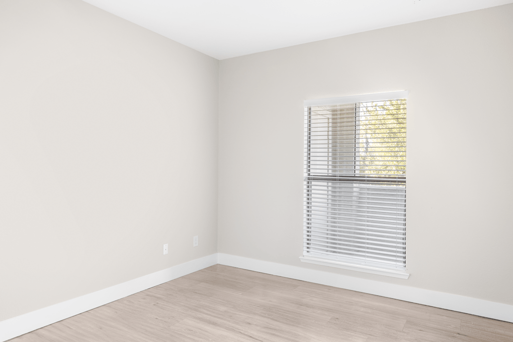 A room with a window and wooden flooring.