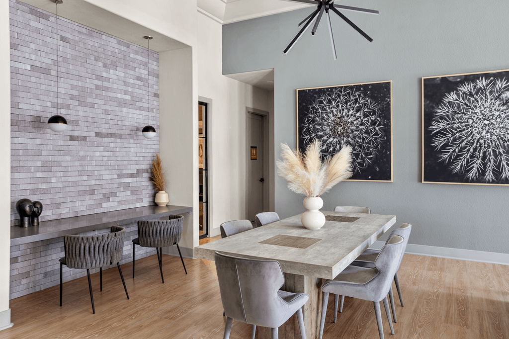 A dining room with a long table and grey chairs.