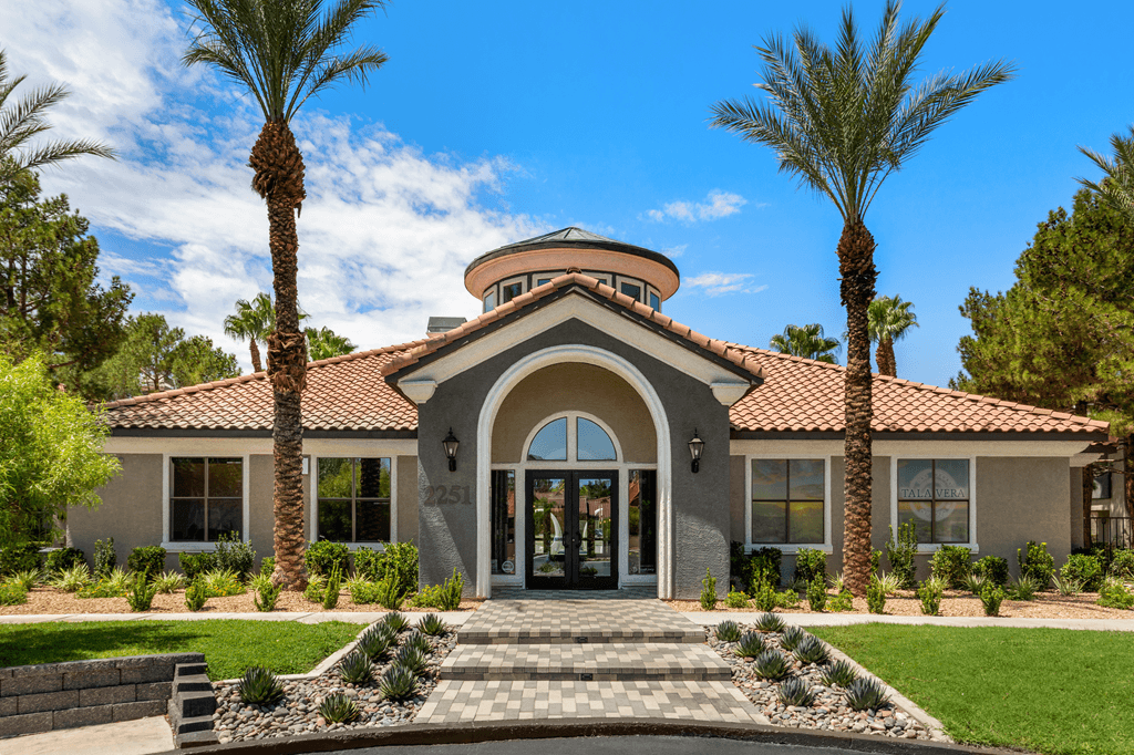 A house with a red-tiled roof and a palm tree in front.