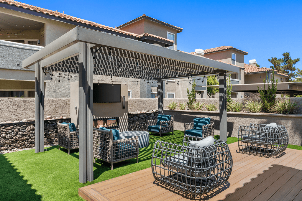 A patio with a pergola and chairs.