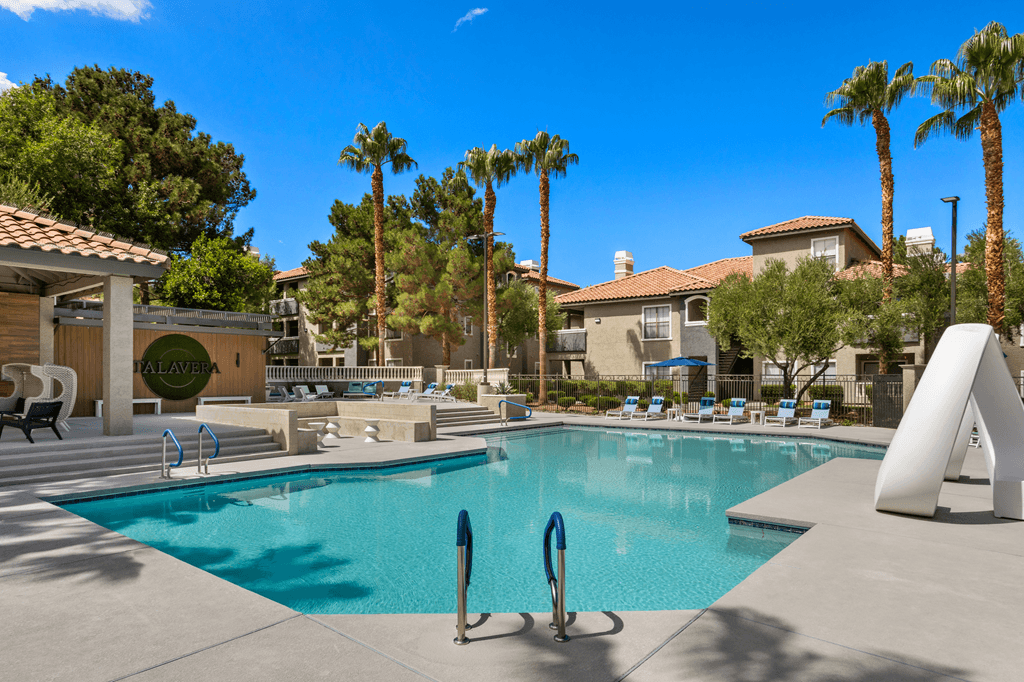 A pool surrounded by palm trees and a white sculpture.
