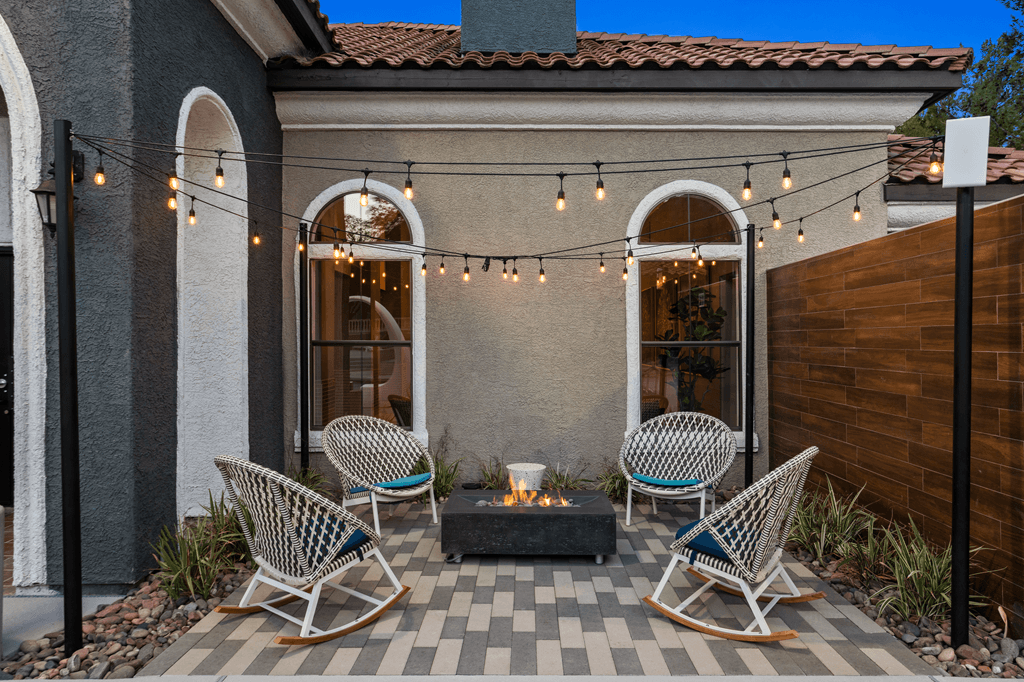 A patio with a fire pit and chairs.