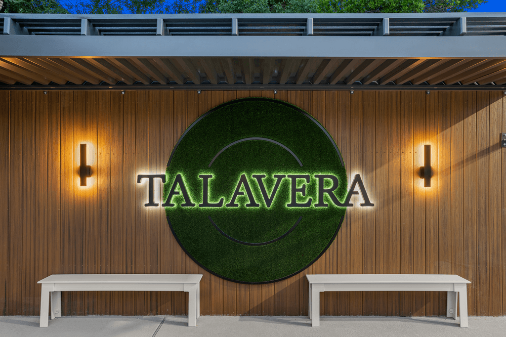 A wooden wall with a sign that says Talavera and two white benches in front.