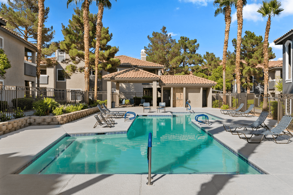 A swimming pool surrounded by lounge chairs and palm trees.