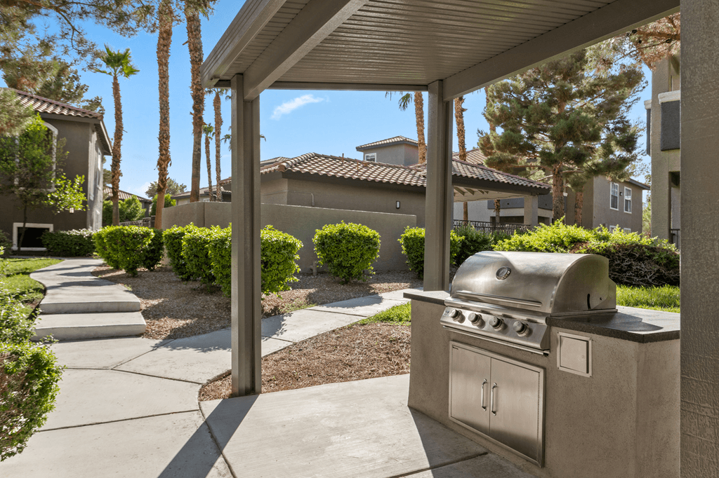 A silver outdoor grill is on a patio.