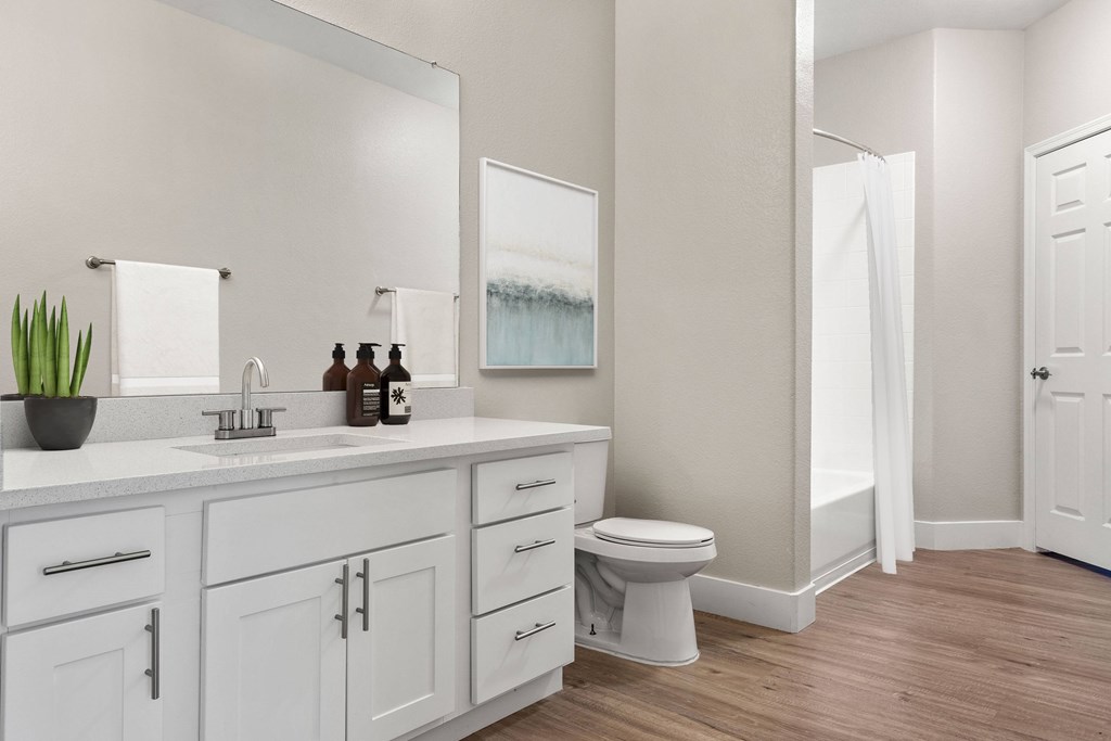 A white bathroom with a toilet, sink, and mirror.