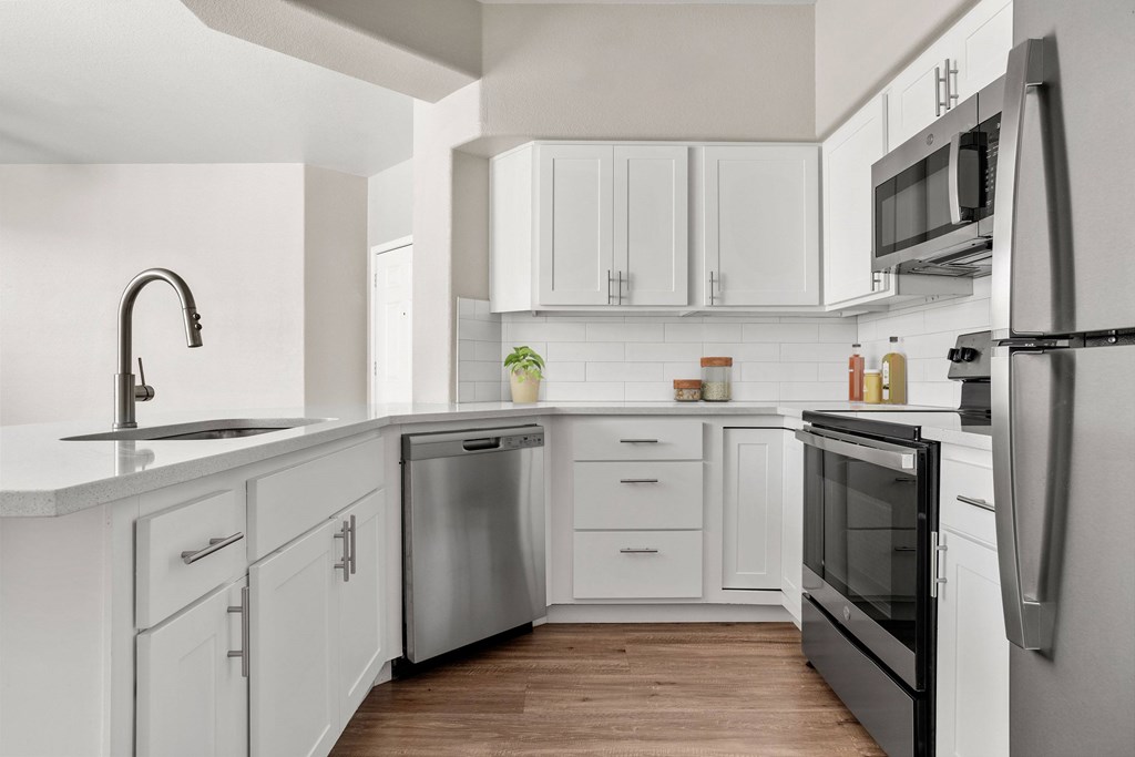 A modern kitchen with white cabinets and stainless steel appliances.