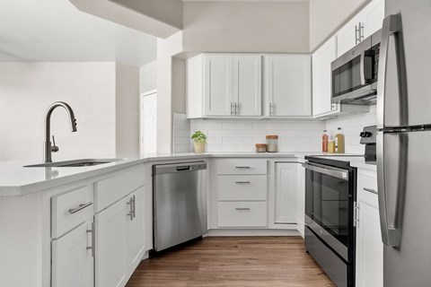 A modern kitchen with white cabinets and stainless steel appliances.