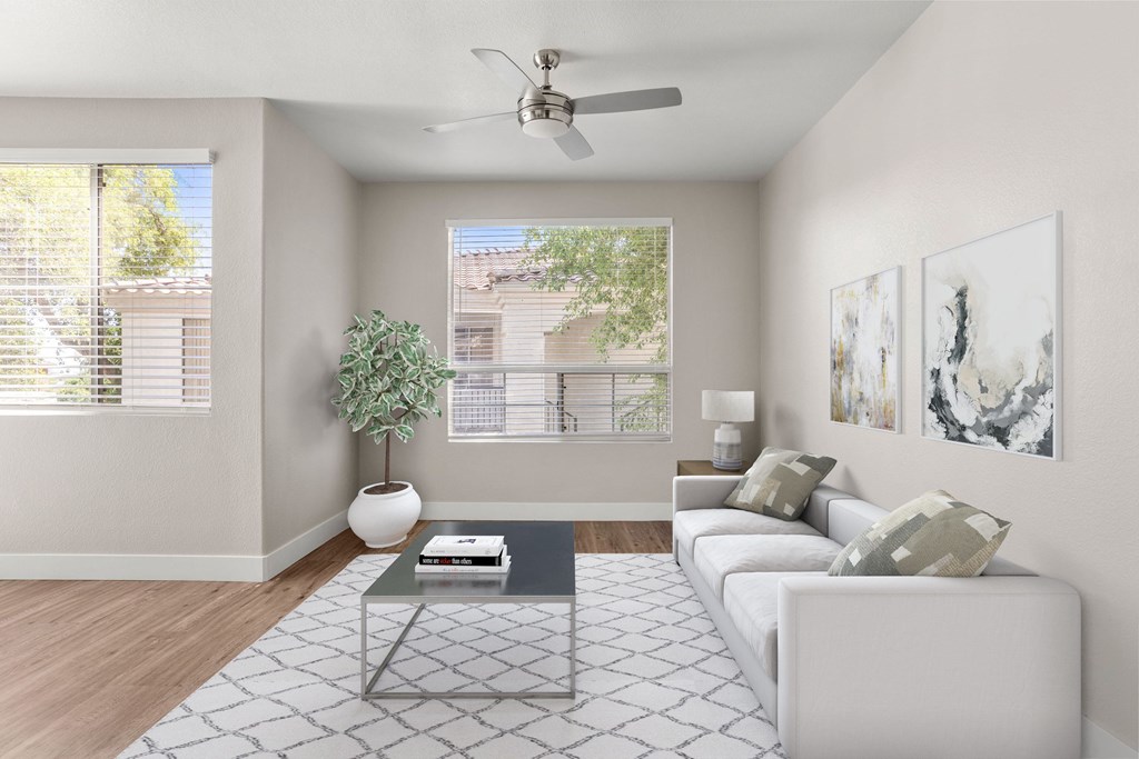 A living room with a white couch, a plant, and a fan.
