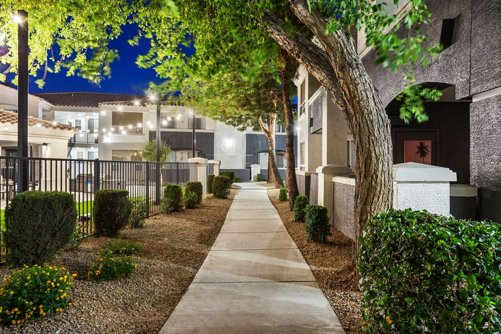 A pathway leads through a landscaped area with a tree and shrubs on either side.