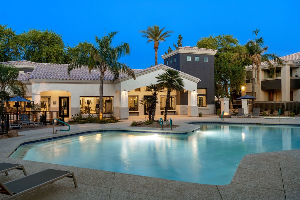 A swimming pool in front of a building with palm trees.