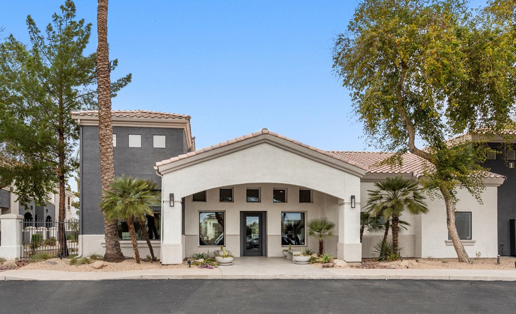 A building with a white facade and a red tile roof is surrounded by trees.