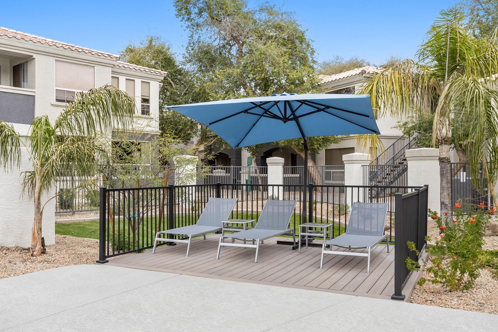 A patio with a blue umbrella and chairs.