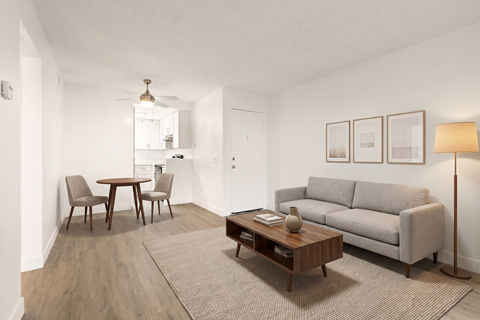 A living room with a grey couch, a coffee table, and a dining table with chairs.