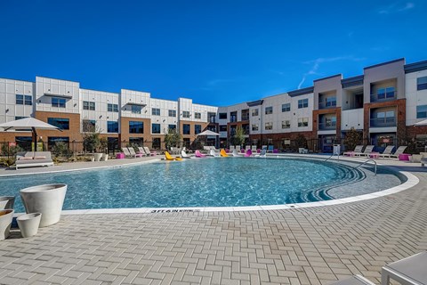 A swimming pool in front of a building with a clear blue sky.