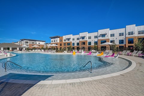 A large swimming pool in front of a building with a clear blue sky above.