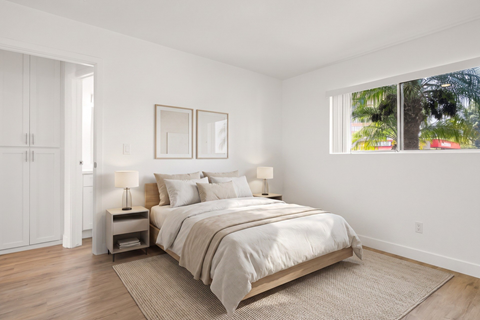 A bedroom with a large bed, two nightstands, and a window.
