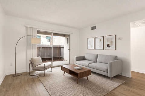 A living room with a grey couch, a chair, a table and pictures on the wall.