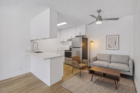 A modern kitchen with white cabinets and a wooden floor.