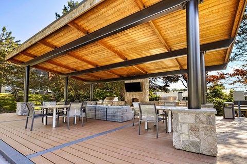 A wooden patio with a table and chairs under a wooden roof.