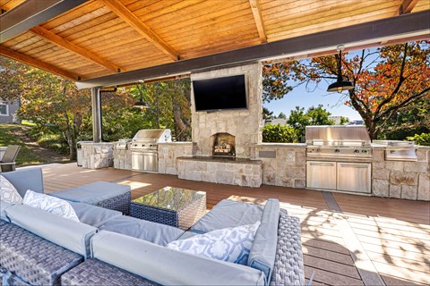 A patio with a stone fireplace and grey couches.