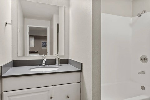 A bathroom with a sink, mirror, and shower.