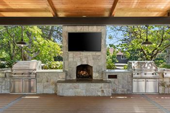 A stone fireplace with a TV above it and a grill to the left.