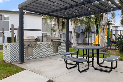 A picnic area with a grill and a table under a canopy.
