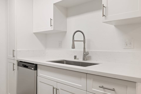 A kitchen with white cabinets and a silver dishwasher.