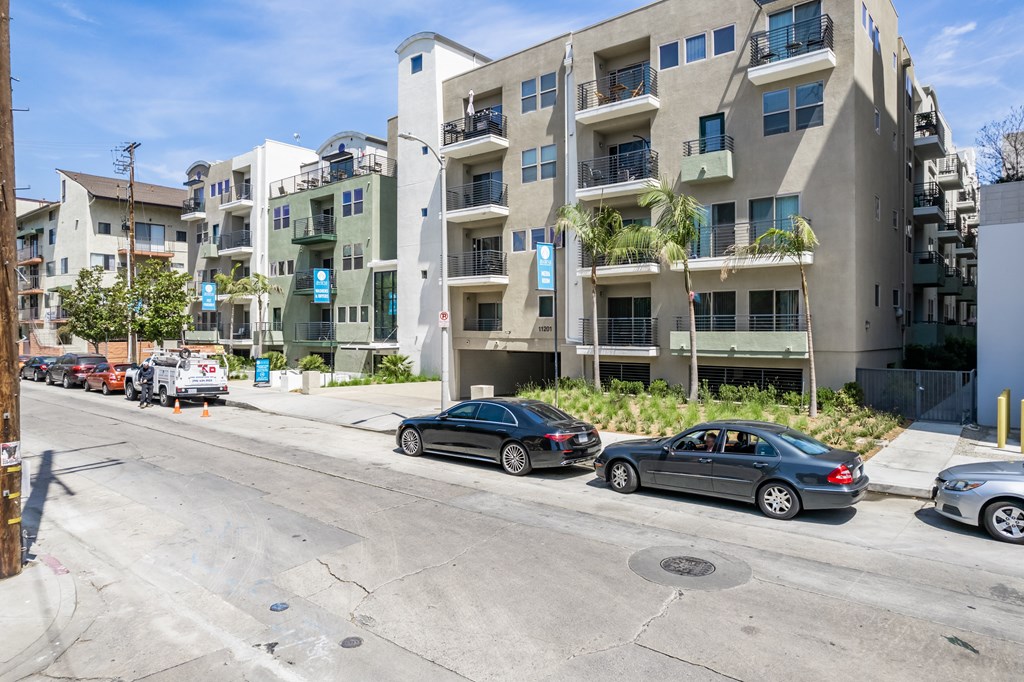 A black car is parked on the street in front of a building.
