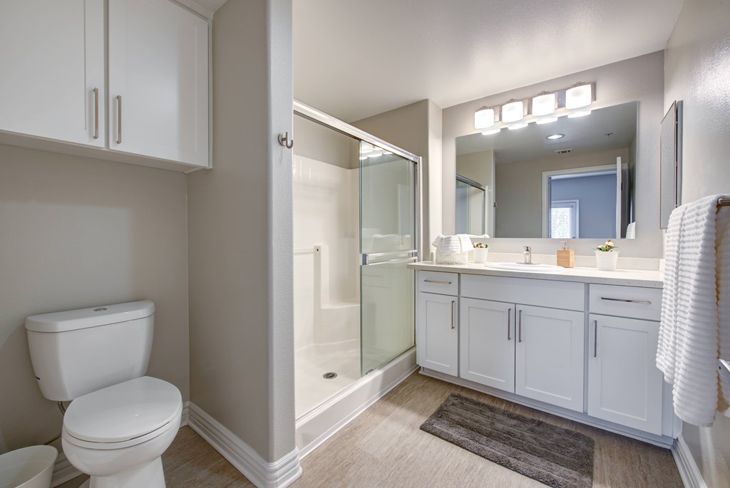 A white bathroom with a toilet, sink, and mirror.