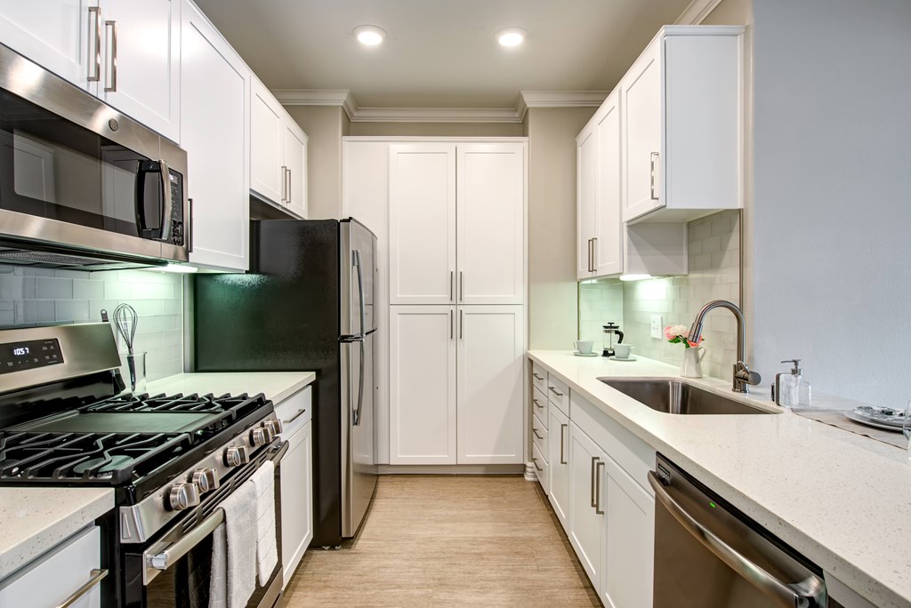 A kitchen with black and white appliances and white cabinets.