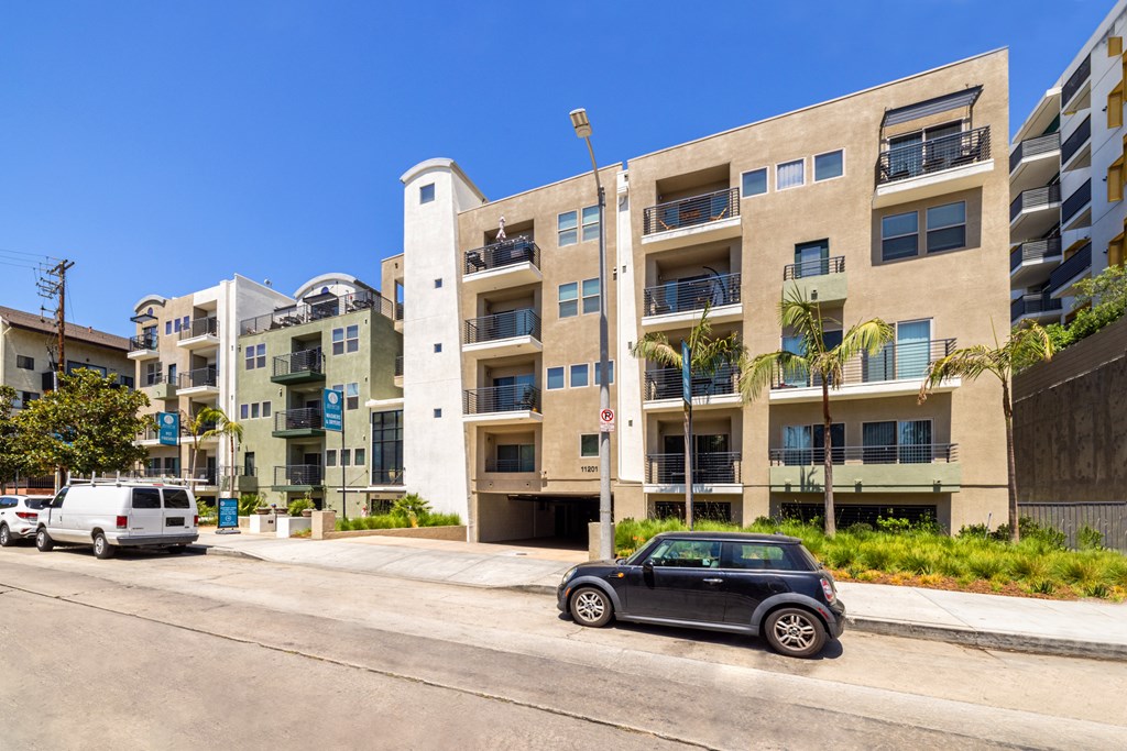 A black car is parked on the side of a street in front of a building.