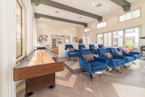 A pool table is in the middle of a room with blue chairs.