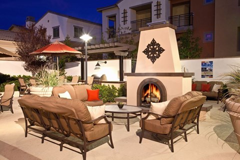 A patio with a fireplace and chairs.